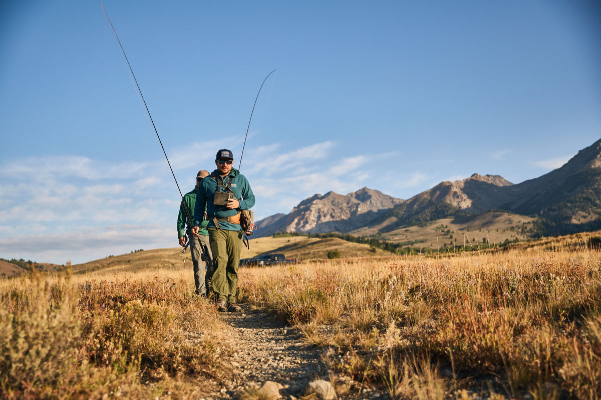 Two men in Steely Zips Rocky Mountain Grid Fleece walking on a dirt trail to the Big Wood River with the Boulder Mountains in the background.  They are dressed in outdoor fishing apparel, with rugged mountains in the background.